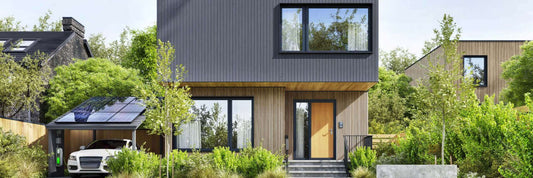 Modern home with solar panels and electric car charging station surrounded by greenery.